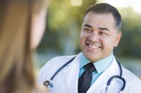 Hispanic Male Doctor or Nurse Talking With a Patient Outdoors.